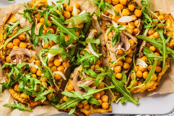 Green vegan pizza with pesto, chickpeas, champignons and arugula. Plant based diet concept.