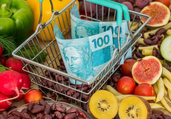 Shopping basket with Brazilian money, around food products, vegetables and fruits. The concept of inflation, rising prices and more expensive food