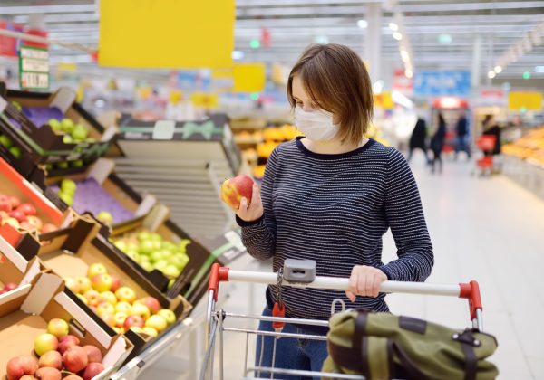 Young woman wearing disposable medical mask shopping in supermarket during coronavirus pneumonia outbreak. Protection and prevent measures while epidemic time.