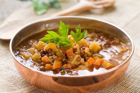 Brown lentil soup in bowl with vegetable, selective focus