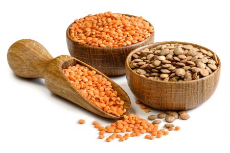 Brown and red lentils in a wooden bowls and scoop isolated on white background. Natural vegetarian food ingredient.